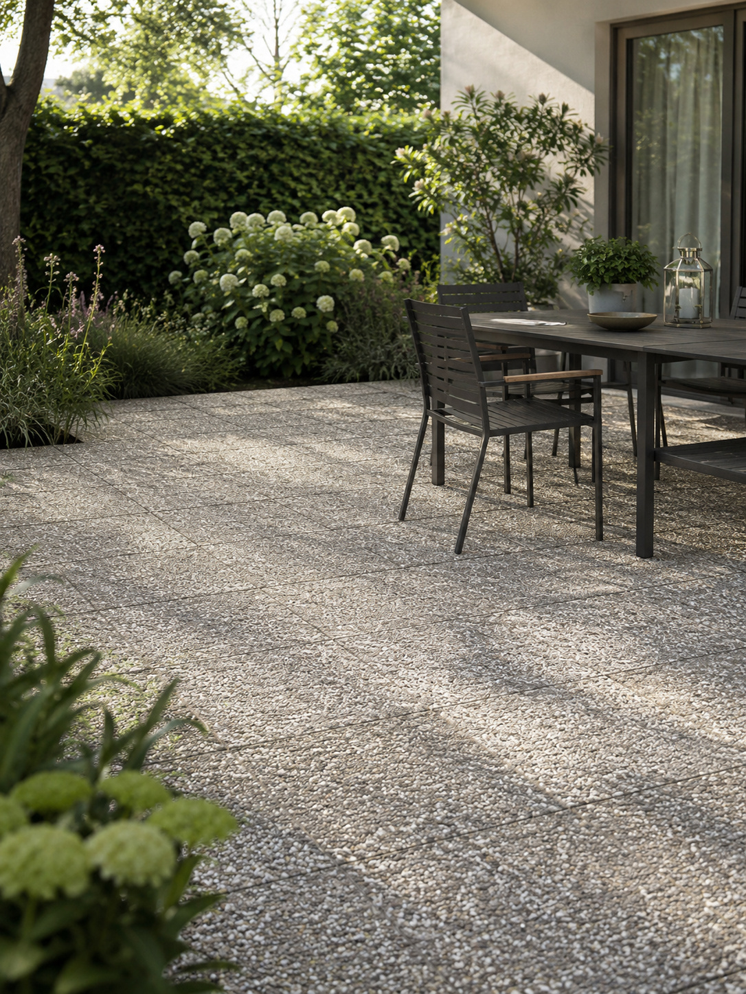 Terrasse mit Waschbetonplatten und Esstisch im Garten